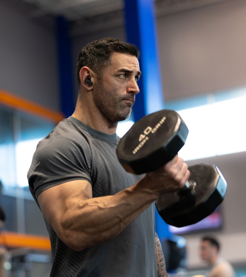 a gym member does bicep curls with a free weight dumb bell at a gym near me in manchester new hampshire