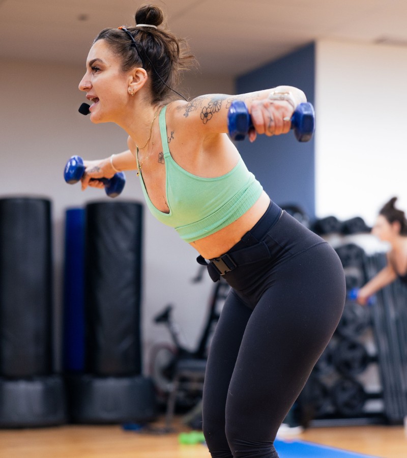 a group fitness instructor shows proper form for dumb bell flys during a group exercise class at the workout club gym in salem new hampshire